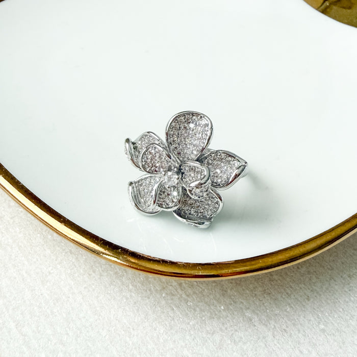 Silver flower-shaped jewelry on a white dish with gold rim -Magnolia Pavé Ring - The Songbird Collection