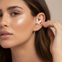 Close-up of a woman wearing a butterfly-shaped earring. ear hook. ear cuff
