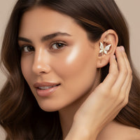 Woman wearing a butterfly-shaped earring / ear hook/ ear cuff with a neutral background
