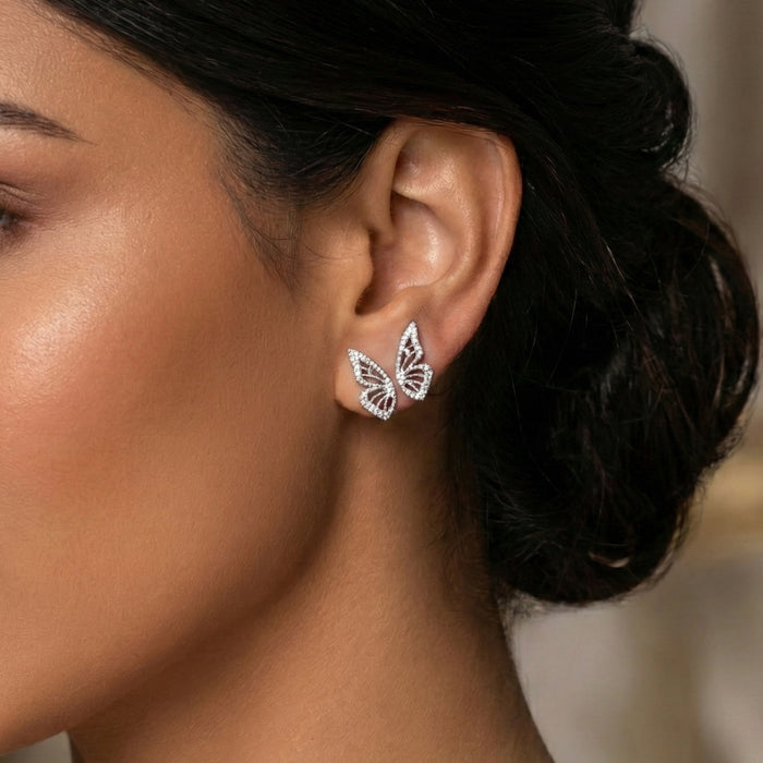 Butterfly-shaped earrings worn by a person with a blurred background