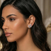 Close-up of a woman wearing butterfly earrings with a neutral background