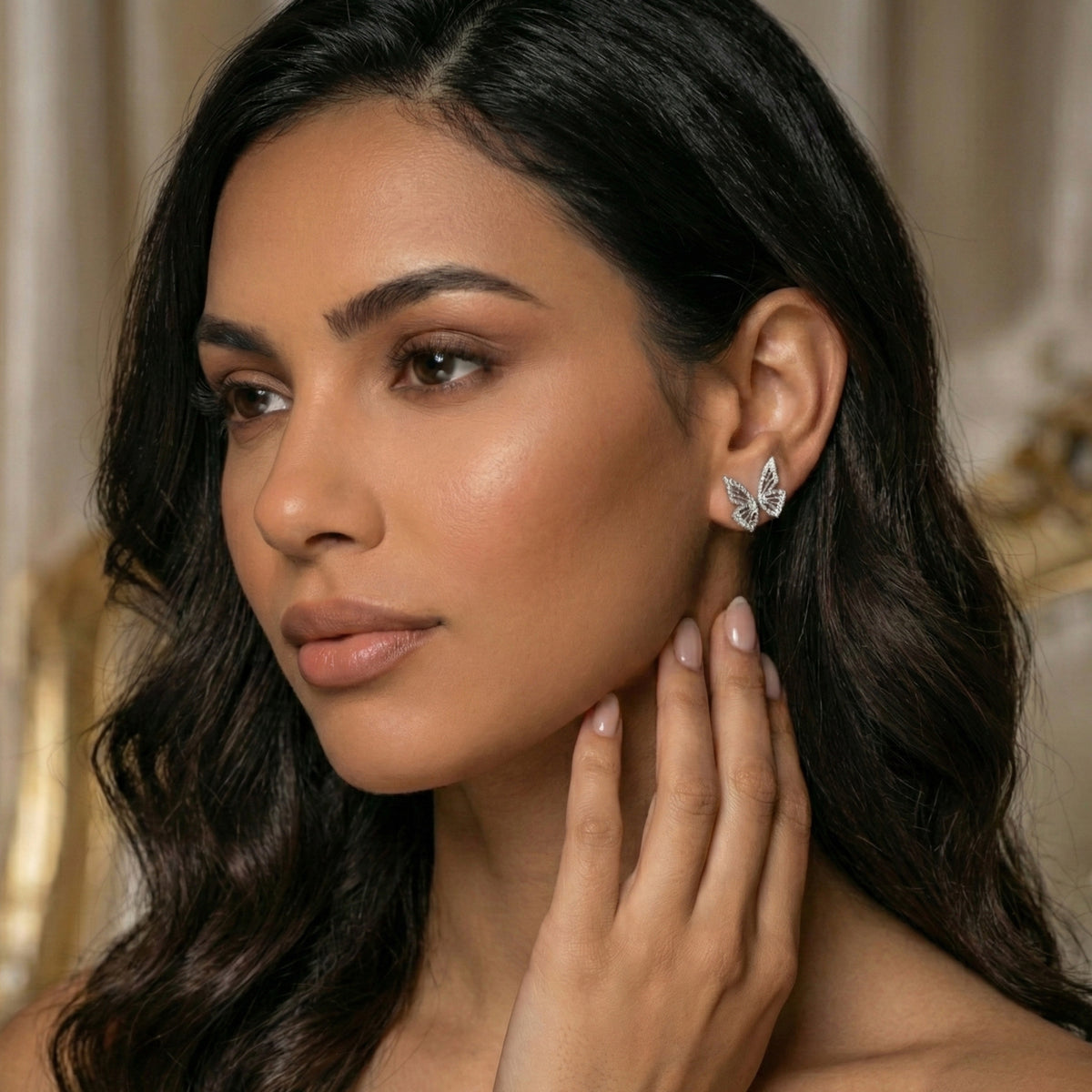 Woman wearing a butterfly earring with a neutral background