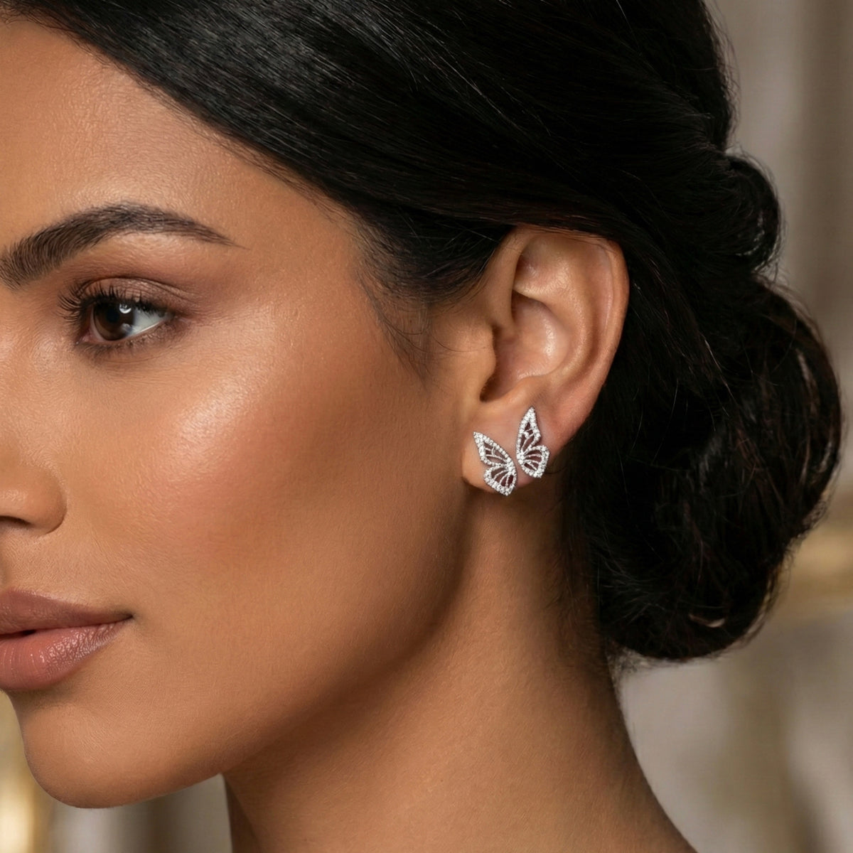 Close-up of a woman wearing butterfly earrings with a blurred background