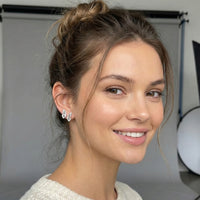 Woman with a stylish hair bun wearing butterfly stud earrings in a studio setting