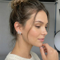 Woman wearing butterfly earrings with a neutral background