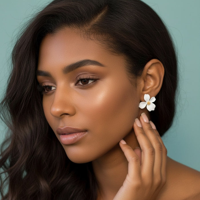 Woman wearing a white flower earring against a teal background