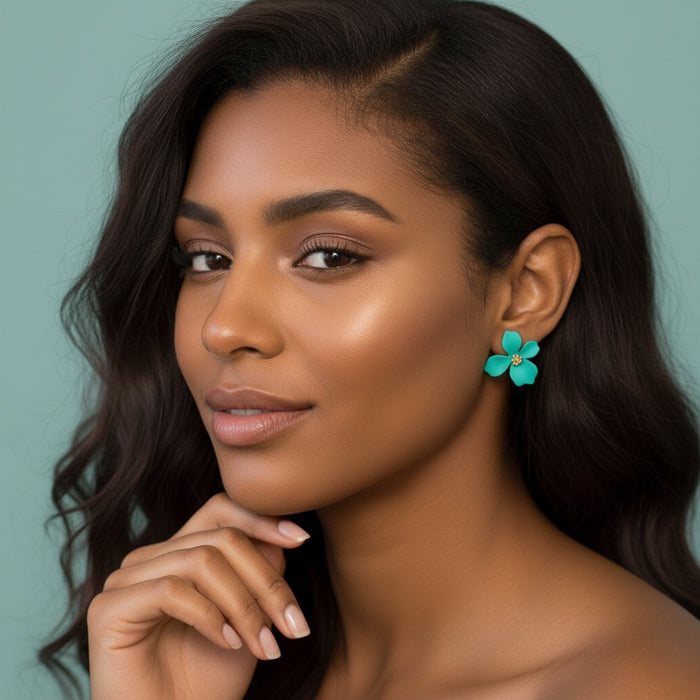 Woman wearing turquoise flower earrings against a teal background