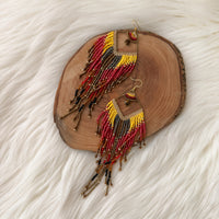 Beaded earrings on a wooden slice with a white fur background