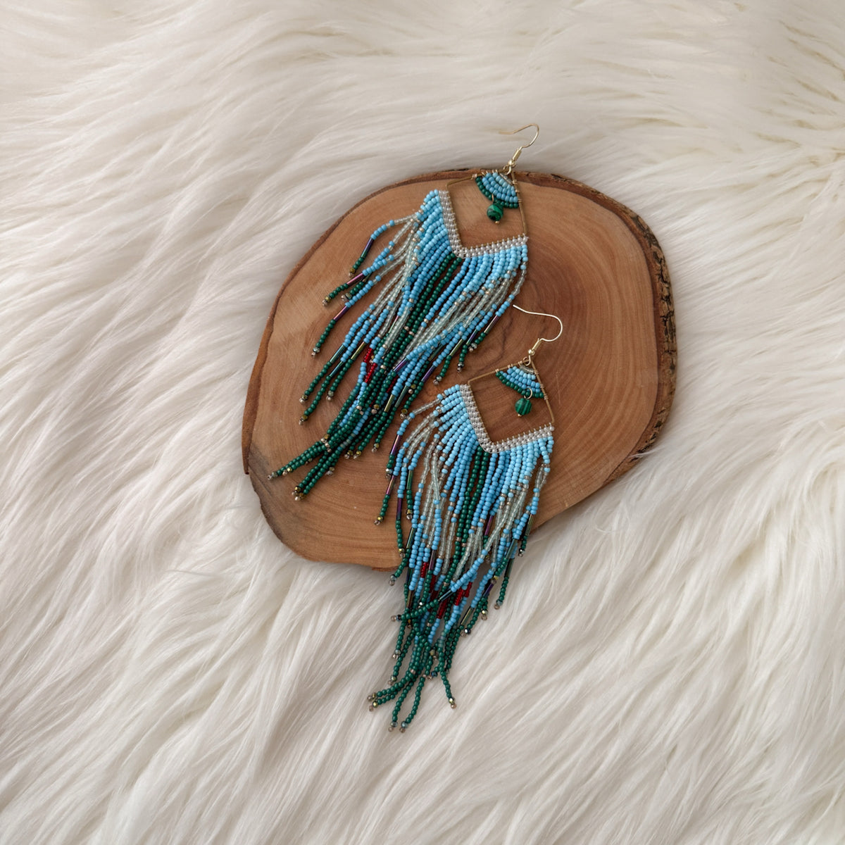 Beaded earrings on a wooden slice with a white fur background