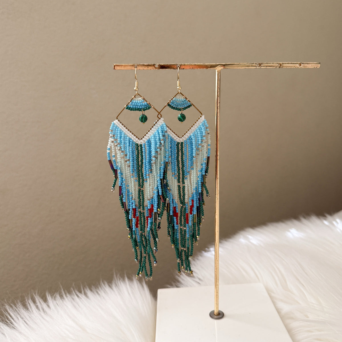 Beaded earrings on a gold stand with a neutral background