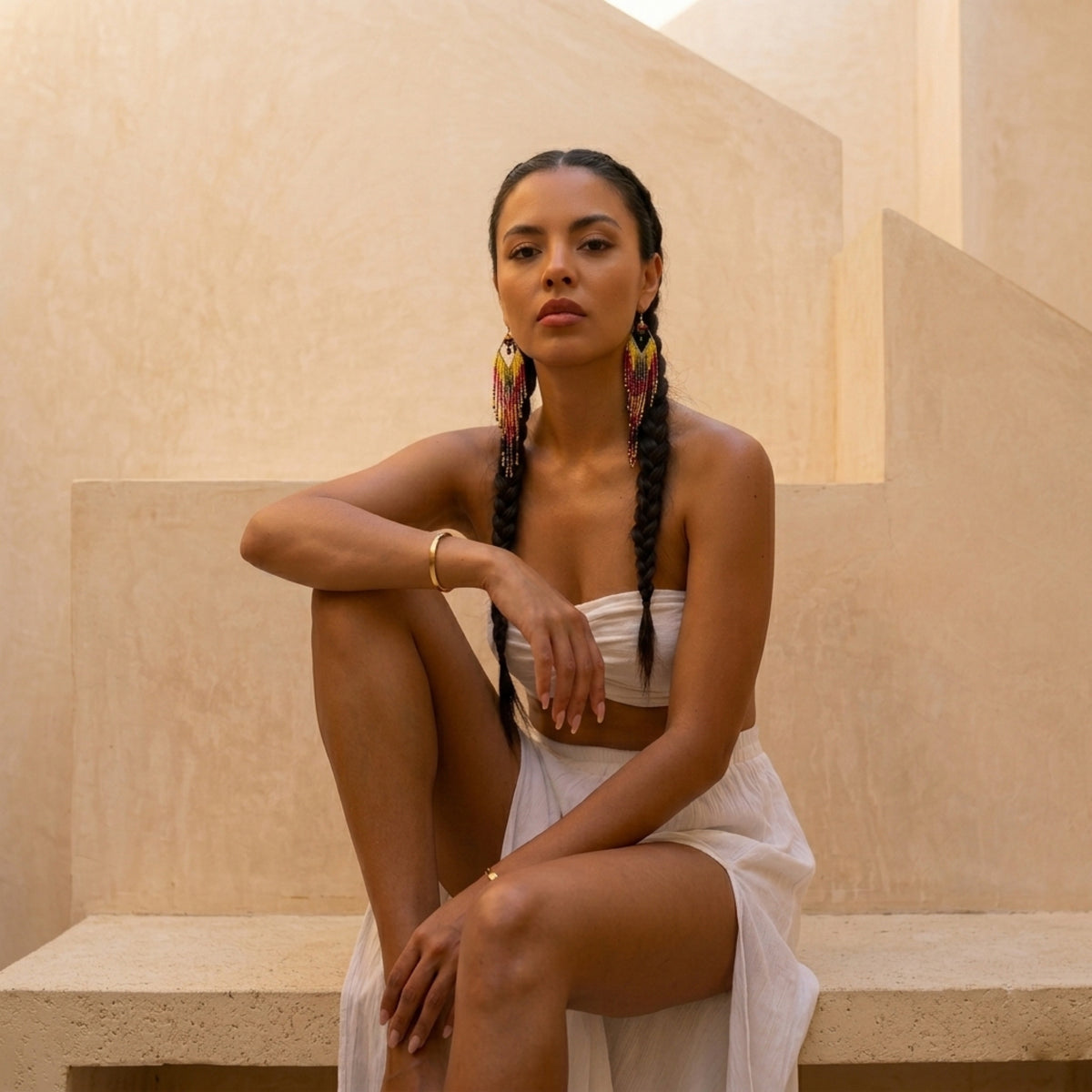 Woman in a white outfit sitting on a stone bench with a neutral background - Mojave Ombre Beaded Statement Earrings