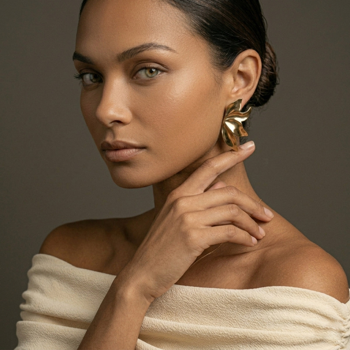 Woman wearing gold earrings with a neutral background. Molten Flame Statement Earrings - The Songbird Collection