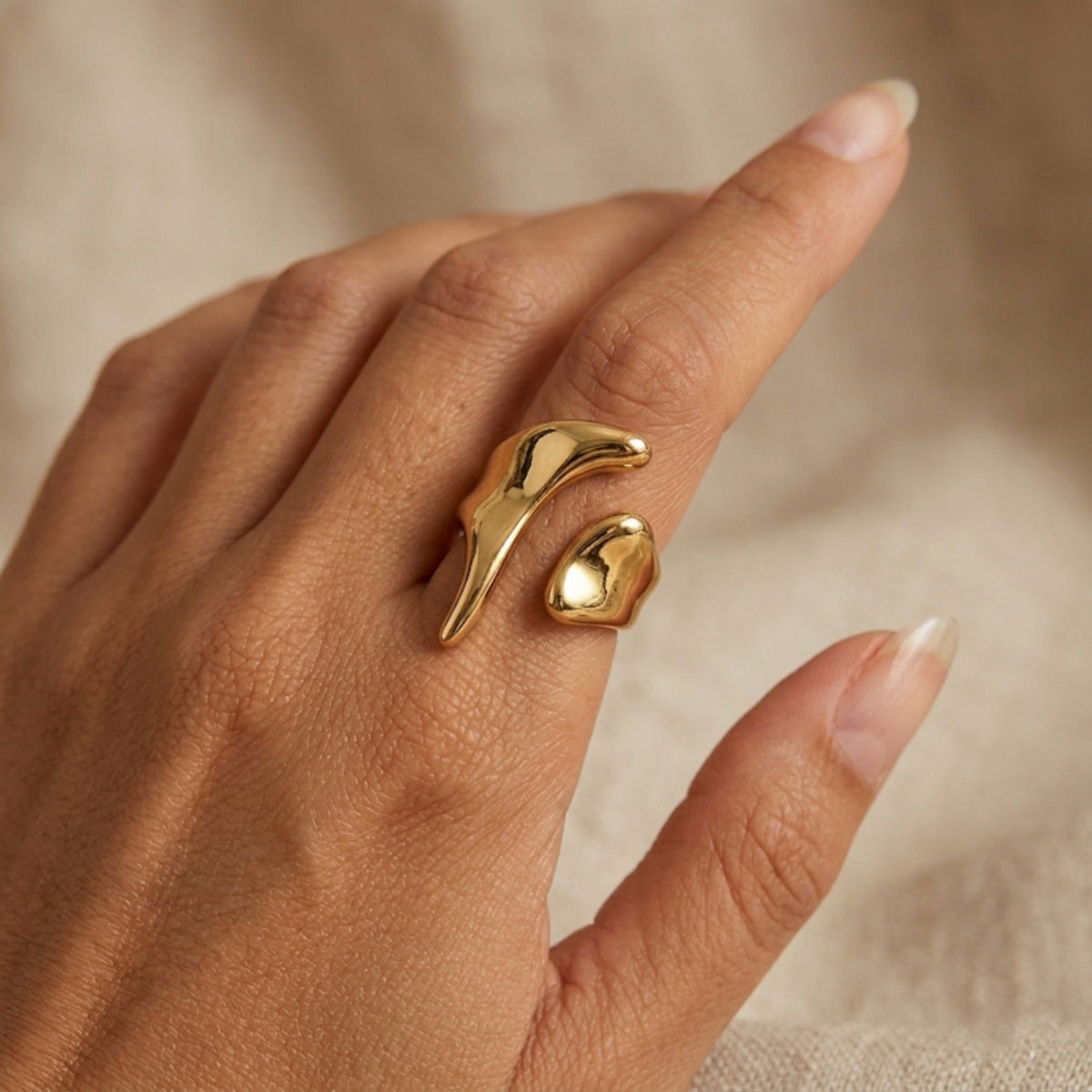 Gold ring on a finger against a neutral background. Molten Gold Statement Ring - The Songbird Collection