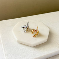Gold and silver earrings on a white stone surface with a beige background. Molten Gold Statement Ring - The Songbird Collection