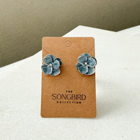 Blue flower earrings on a brown card with 'The Songbird Collection' branding.