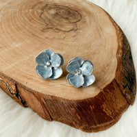 Pair of silver and blue flower-shaped earrings on a wooden surface
