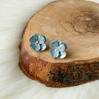blue flower-shaped earrings with silver trimming on a white dish with gold rim - Moonlit Peony Earrings - The Songbird Collection