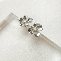 Silver flower-shaped earrings on a white background