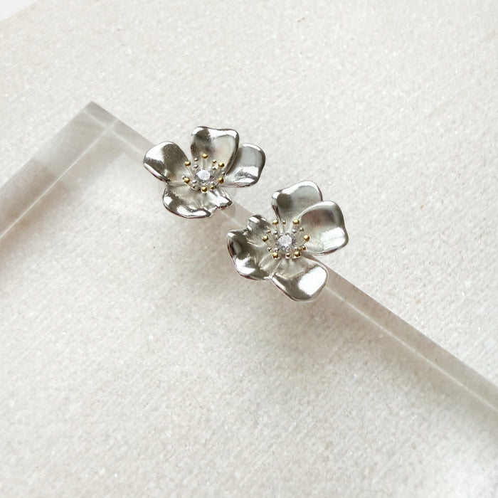 Silver flower-shaped earrings on a white background