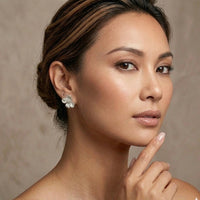 Woman wearing floral earrings against a neutral background