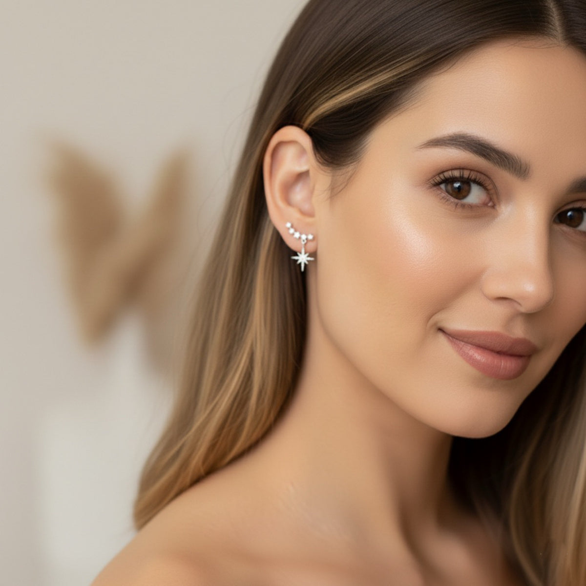 Close-up of a woman wearing star-shaped earrings with a neutral background
