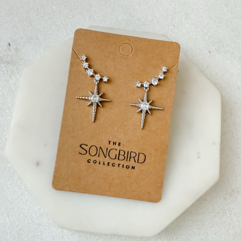 Star-shaped earrings on a 'The Songbird Collection' card against a light background