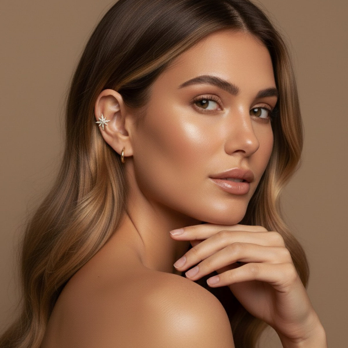 Woman with a neutral expression against a beige background wearing a star shaped ear cuff