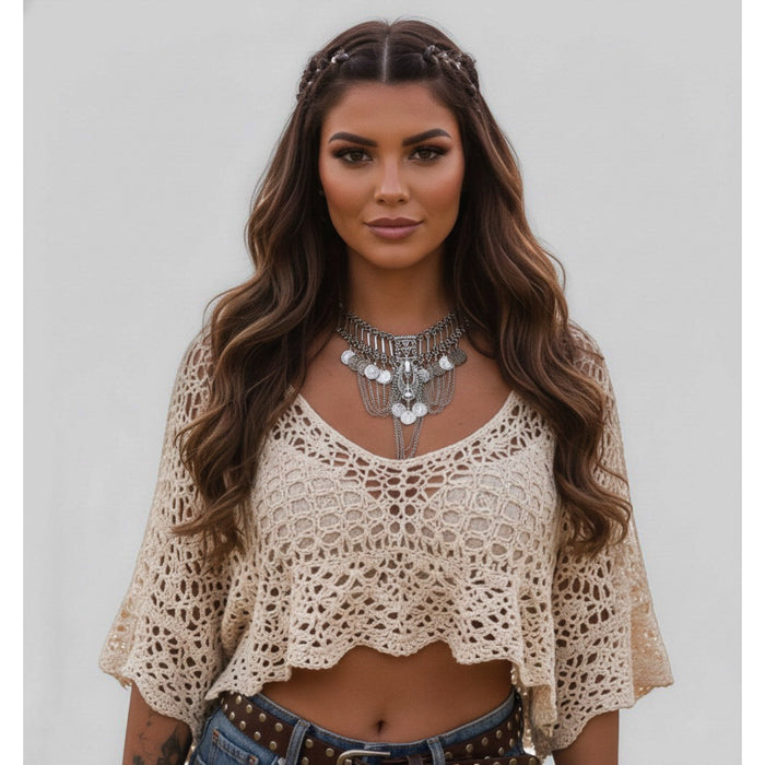Woman wearing a beige crochet top and denim shorts with a neutral background