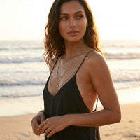 Woman in a black dress standing on a beach with ocean in the background  Peek-a-boo Body Chains - The Songbird Collection