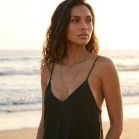 Woman standing on a beach wearing a black dress with thin straps.Peek-a-boo Body Chains - The Songbird Collection