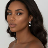 Woman wearing a floral shaped diamond bridal earring against a neutral background