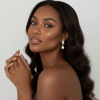 Woman wearing a floral shaped diamond drop earring against a plain background