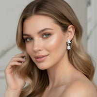 Woman wearing a pair of floral diamond drop bridal earrings with a neutral background