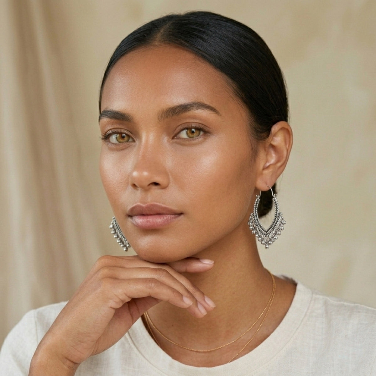 Woman wearing silver hoop earrings against a beige background. Priya_Vintage_Metal_Earrings_-_The_Songbird_Collection_