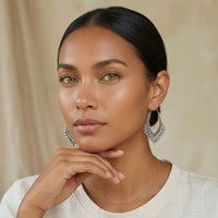 Woman wearing silver hoop earrings against a beige background. Priya_Vintage_Metal_Earrings_-_The_Songbird_Collection_