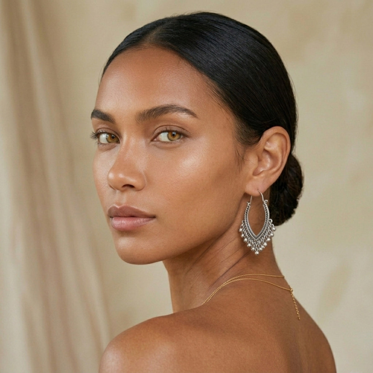 Woman wearing silver hoop earrings with a neutral background. Priya_Vintage_Metal_Earrings_-_The_Songbird_Collection_