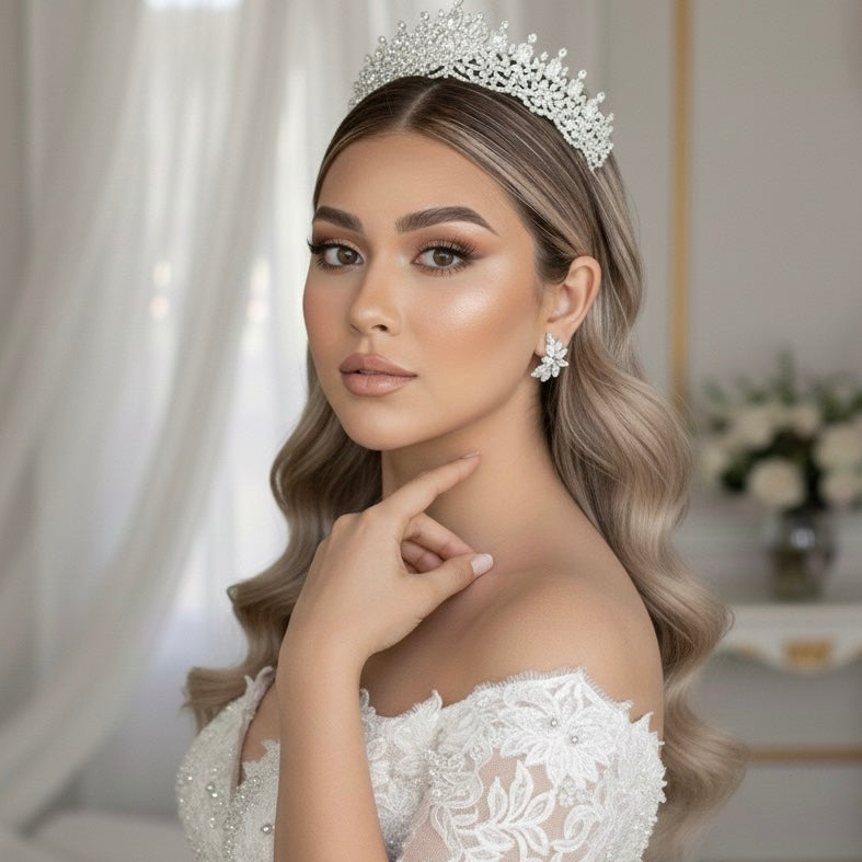 A bride wearing a white wedding dress and tiara with floral petal shaped diamond earringsin a elegant indoor setting