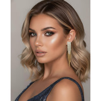 Woman with styled hair and earrings against a neutral background