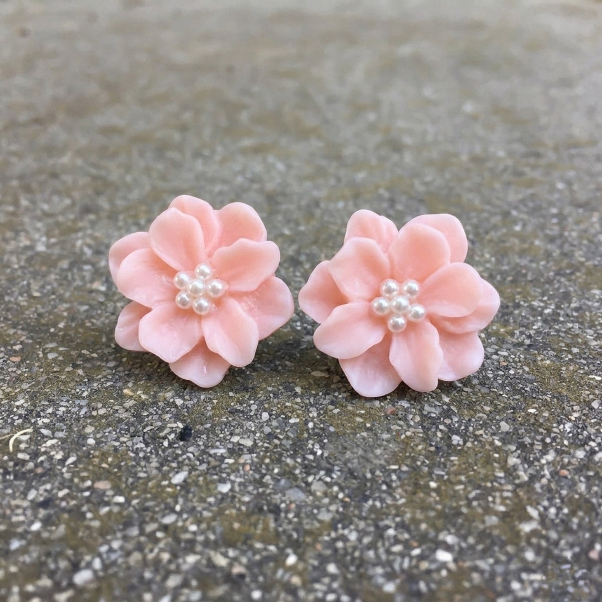 Pair of pink flower earrings with pearl centers on a textured surface. Rosalie Earrings - The Songbird Collection