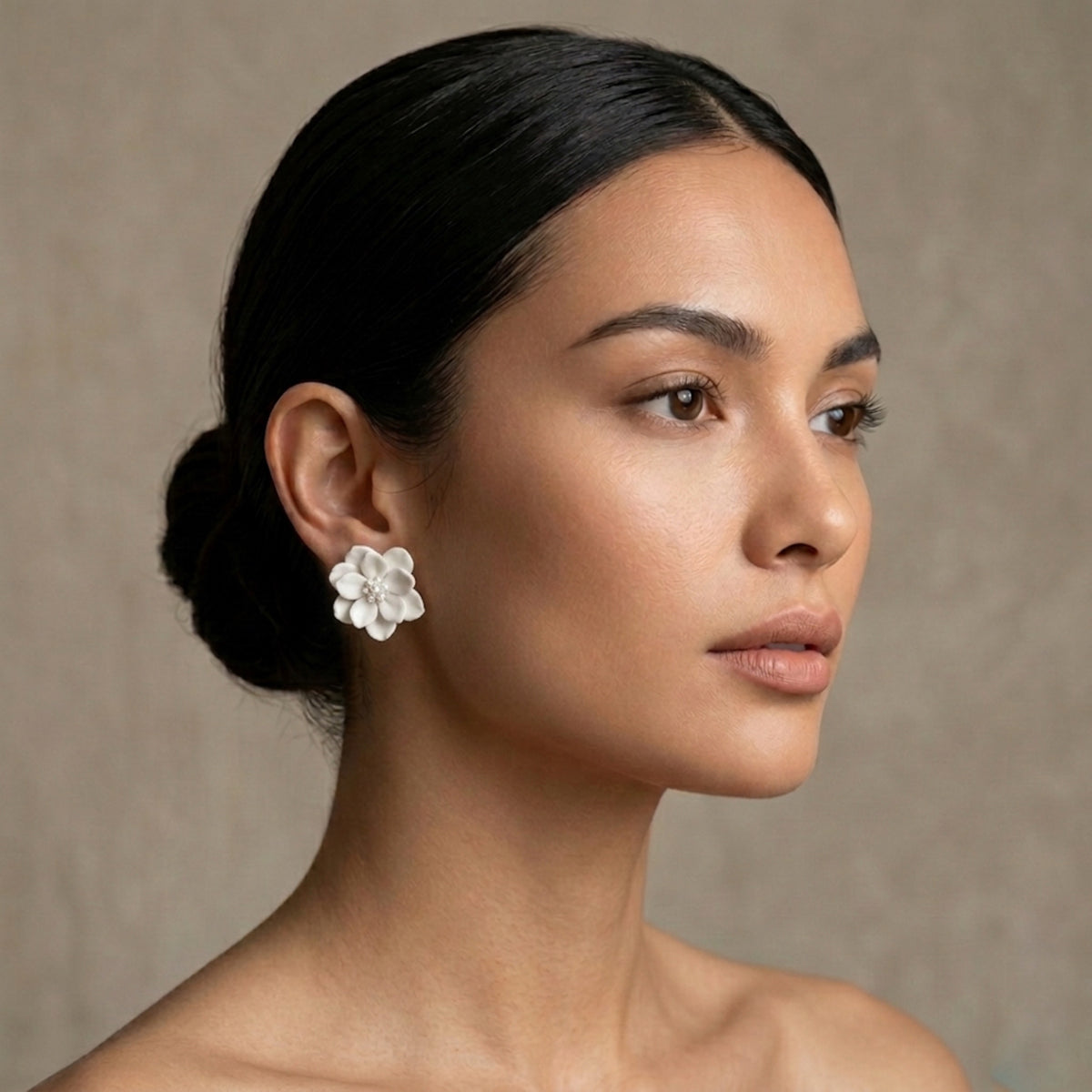 Woman wearing a white floral earring against a neutral background