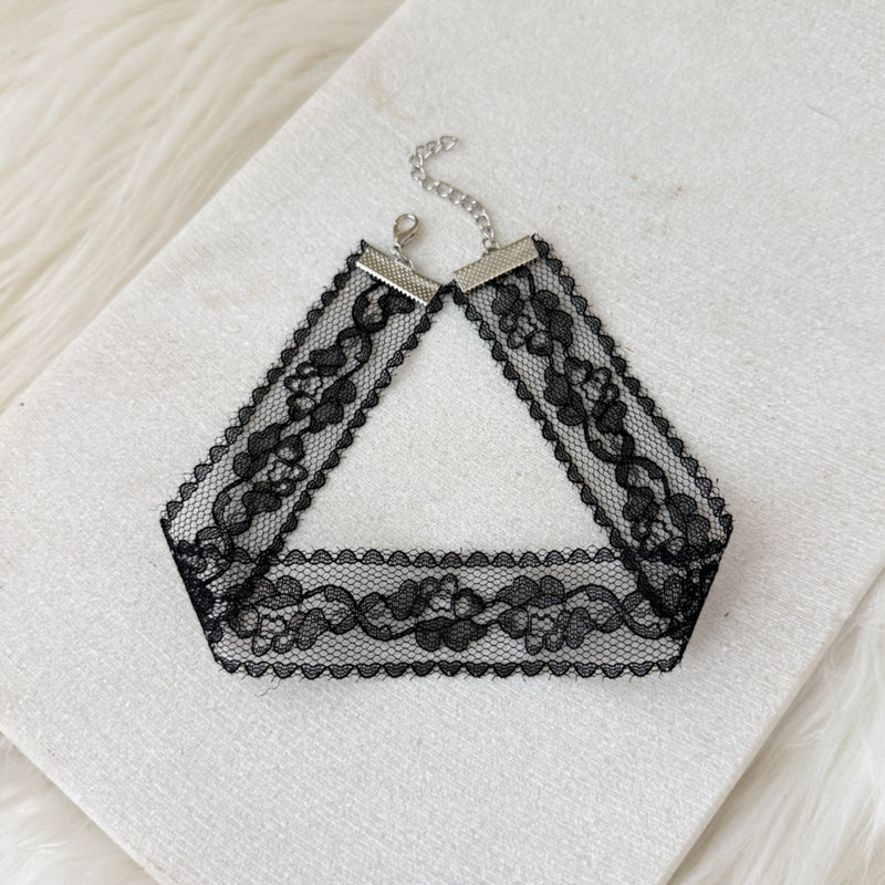 Black lace choker necklace on a textured white surface