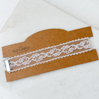 White lace choker  on a brown cardboard holder with 'The Songbird Collection' branding.