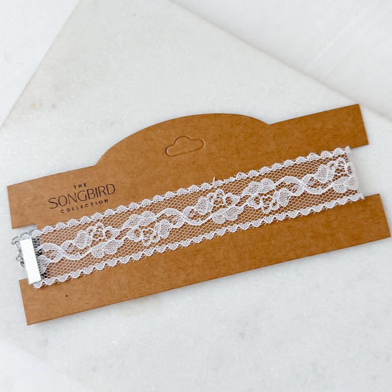 White lace choker  on a brown cardboard holder with 'The Songbird Collection' branding.