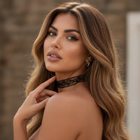 Woman with long, wavy hair wearing a black lace choker against a blurred background