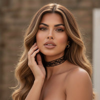Woman with long, wavy hair wearing a black lace choker against a blurred background