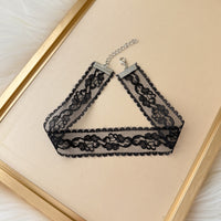 Black lace choker necklace on a beige background