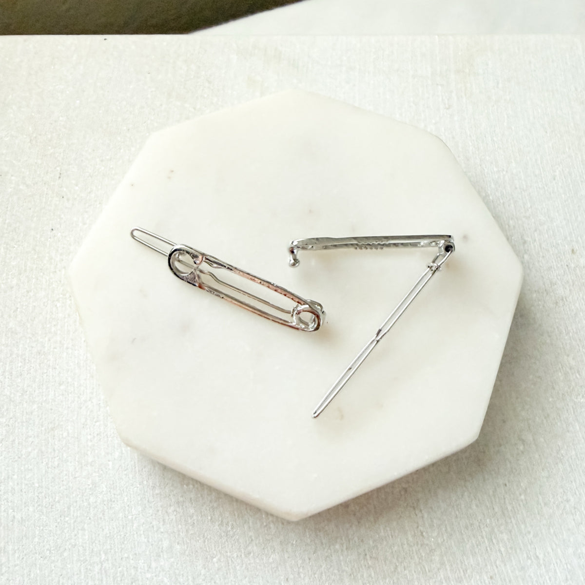 Two silver-toned safety pin style hair pins displayed on a white octagonal stone tray against a light fabric background.  Safety Pin Hair Pin Set - The Songbird Collection