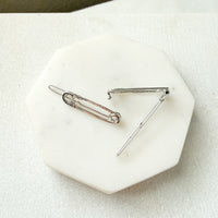 Two silver-toned safety pin style hair pins displayed on a white octagonal stone tray against a light fabric background.  Safety Pin Hair Pin Set - The Songbird Collection