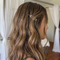 A close-up side profile of a woman with long, wavy brown hair with blonde highlights, wearing a silver safety-pin hair clip.  Safety Pin Hair Pin Set - The Songbird Collection