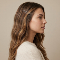 A woman in profile wearing a small silver safety-pin style hair clip on her brown hair, against a plain beige background.  Safety Pin Hair Pin Set - The Songbird Collection
